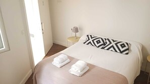 Una habitación de hotel con una cama, dos toallas, una lámpara y una puerta.
