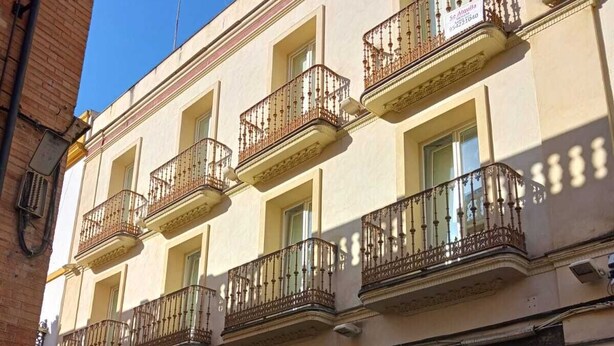Un edificio con varios balcones, un letrero que dice 'Keno' en la planta baja y un cielo azul despejado.