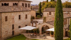A courtyard with stone buildings, outdoor seating, and a central archway.