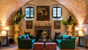 A cozy room with two green sofas, a fireplace, and a large window with a painting above it.