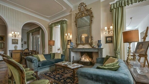 Ein klassisches Wohnzimmer mit Kamin, grünen Polstersofas und traditioneller Einrichtung.