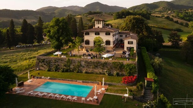 Une vaste villa dotée d’une piscine, entourée d’une végétation luxuriante et de collines.
