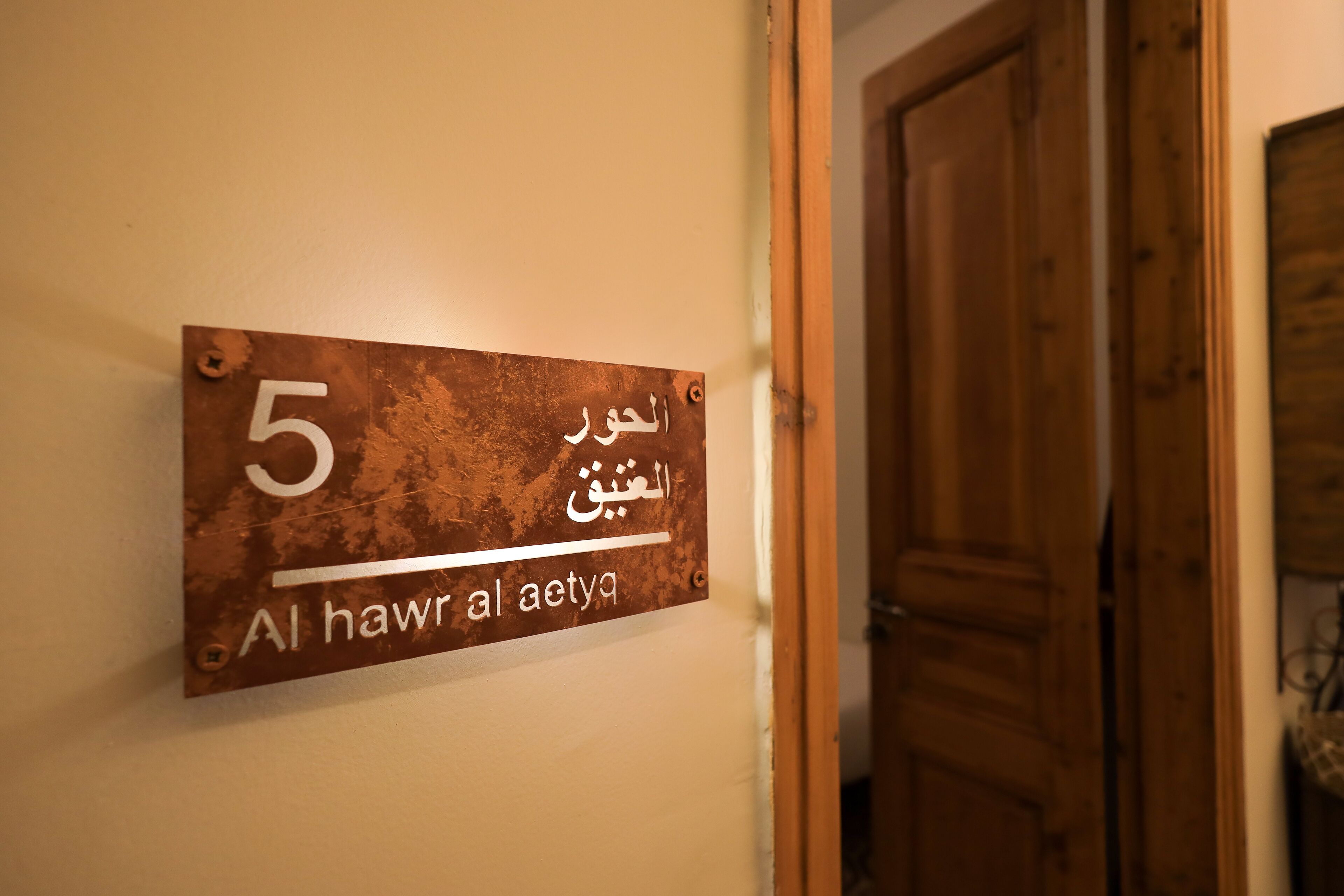 A metal sign with Arabic text and the number 5, mounted on a wall.