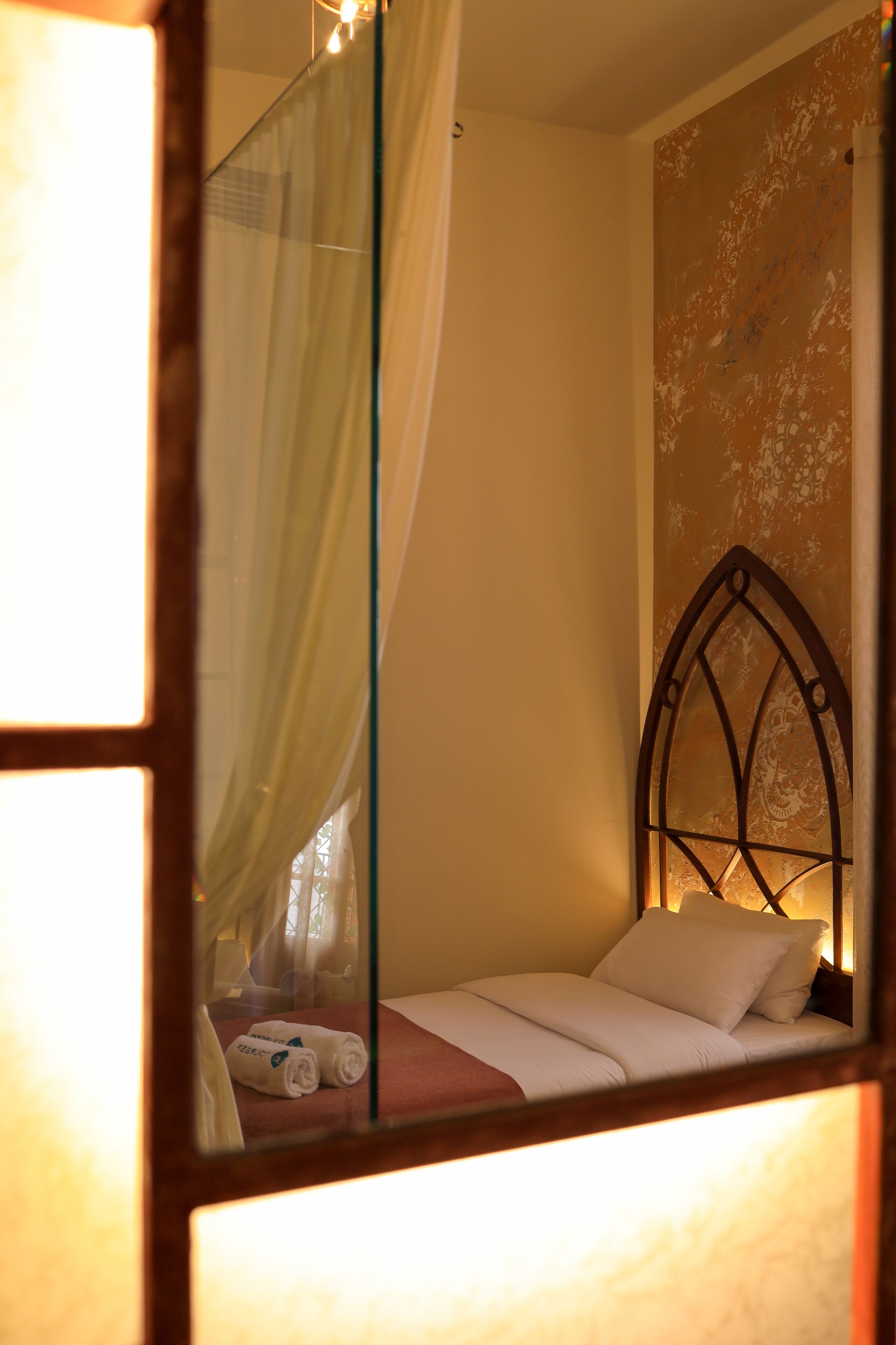 A bedroom with a bed, a canopy, and a decorative wall.