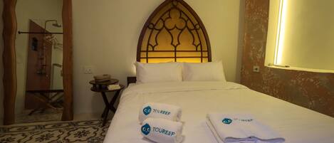 Una habitación de hotel con una cama grande, un cabecero de madera y dos toallas con el logotipo "TOUREEF".