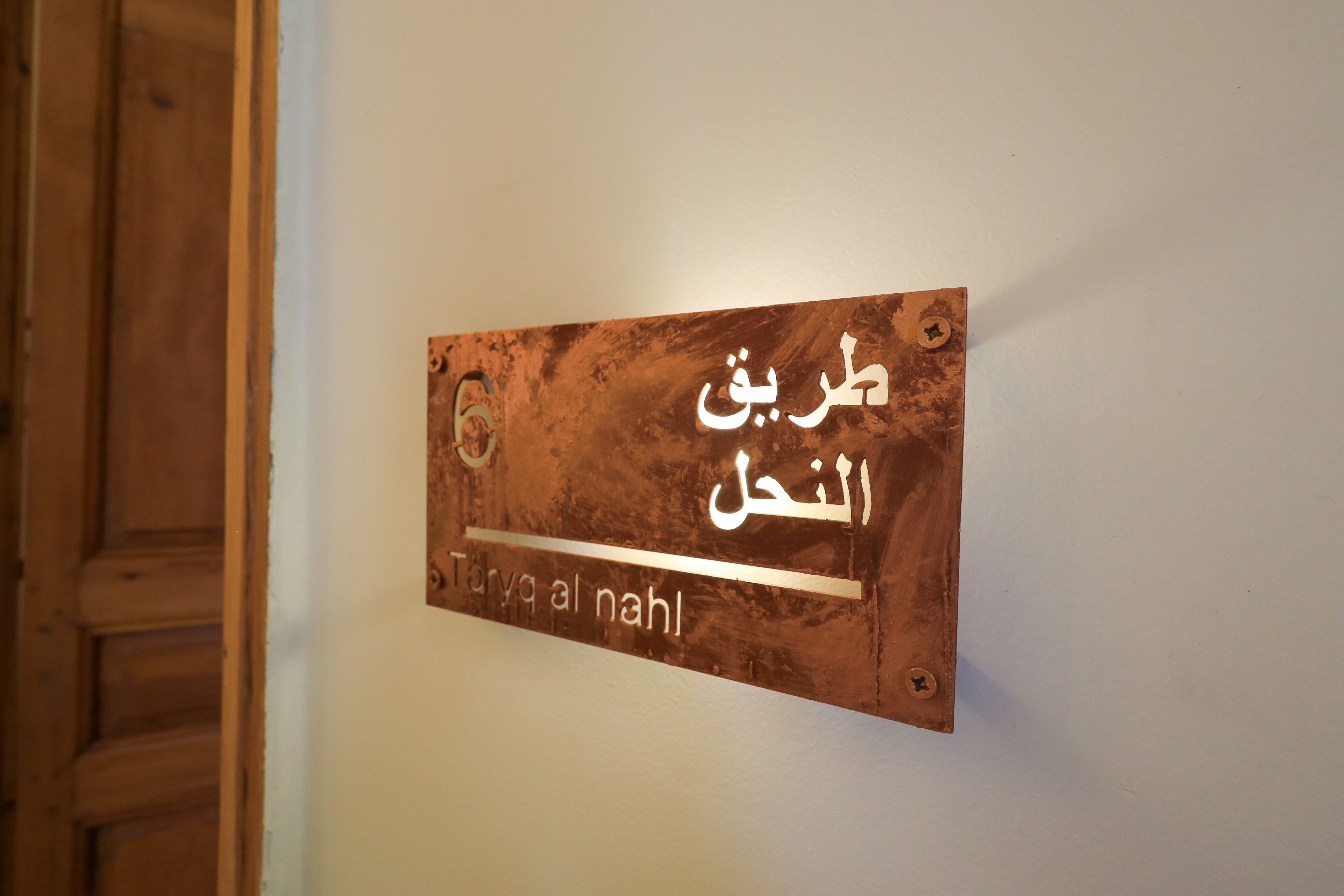 A sign with Arabic text on a wall.