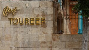 A stone wall with a gold sign that reads "Bet TOUREEF". - Beit Toureef - HOME (Beirut)