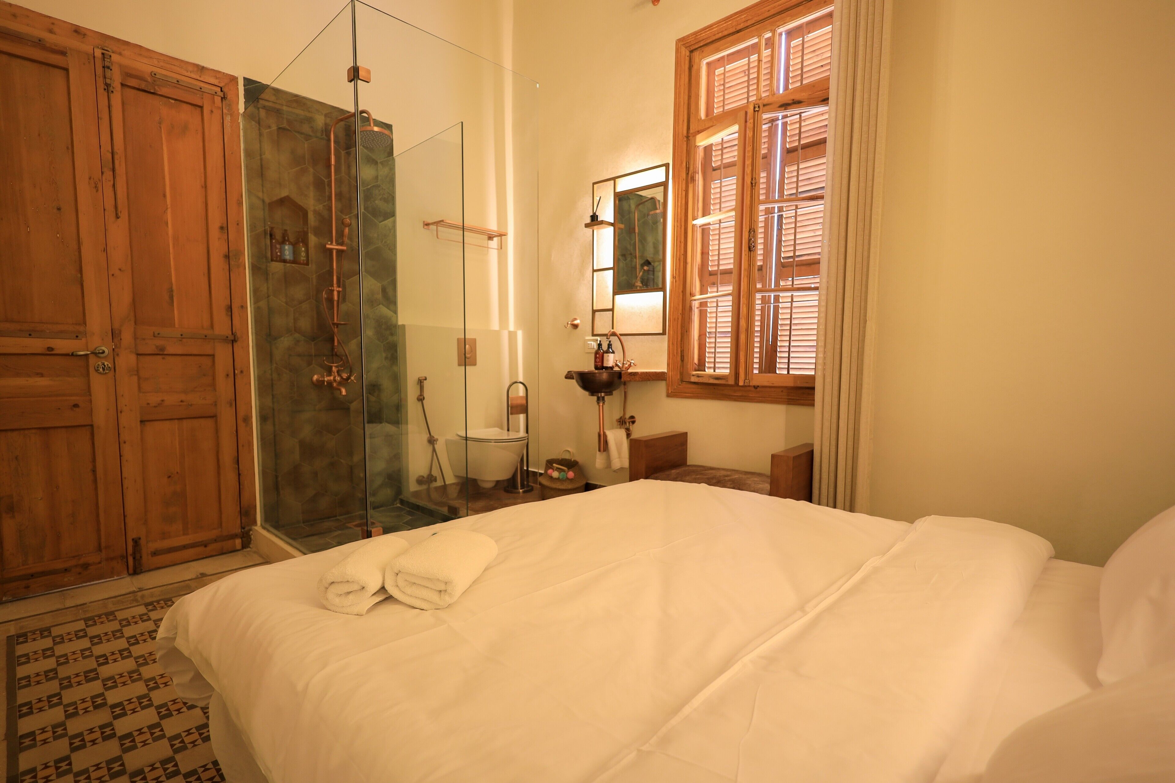 Een slaapkamer met een groot bed, een houten garderobe en een douchecabine met glazen wanden.