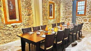 A dining area with a stone wall, wooden table, and chairs. - Beit Toureef - HOME (Beirut)