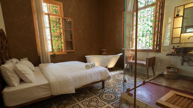 A bedroom with a bed, a bathtub, and a shower area. - Beit Toureef - HOME (Beirut)