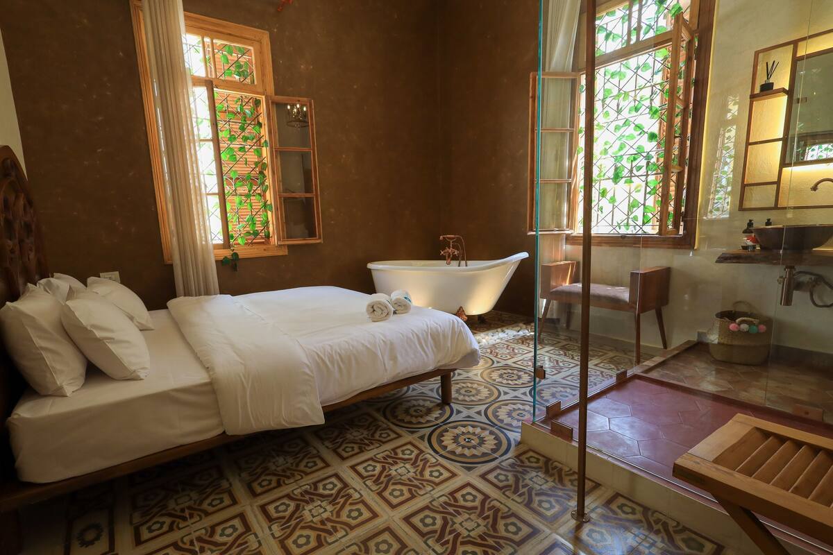 Un dormitorio con cama, bañera y zona de ducha.