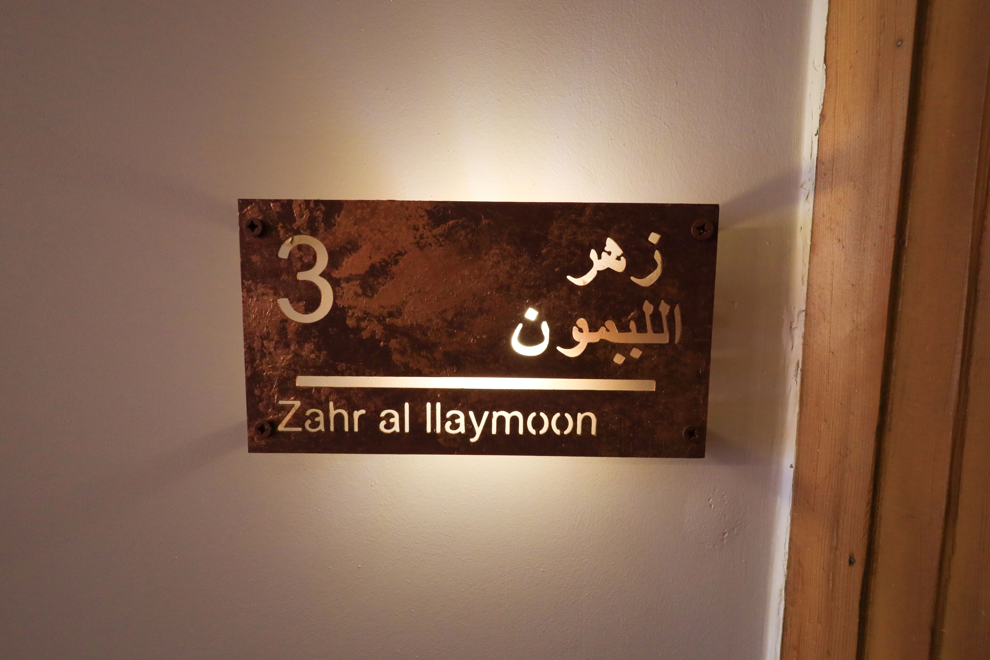 Une affiche sur un mur, avec un texte en arabe et sa traduction en anglais : « Zahr al Laymoon ».