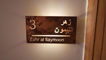 Une affiche sur un mur, avec un texte en arabe et sa traduction en anglais : « Zahr al Laymoon ».