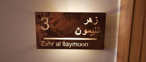 Une affiche sur un mur, avec un texte en arabe et sa traduction en anglais : « Zahr al Laymoon ».
