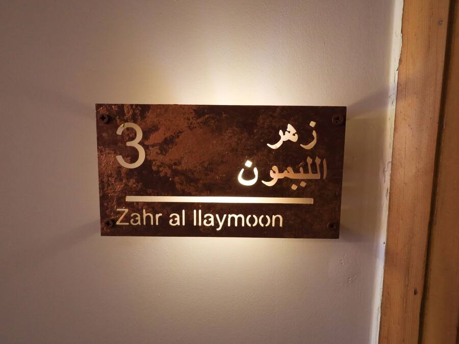 Une affiche sur un mur, avec un texte en arabe et sa traduction en anglais : « Zahr al Laymoon ».