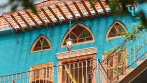 A turquoise building with a balcony, a wooden staircase, and a hanging light fixture. - Beit Toureef - HOME (Beirut)