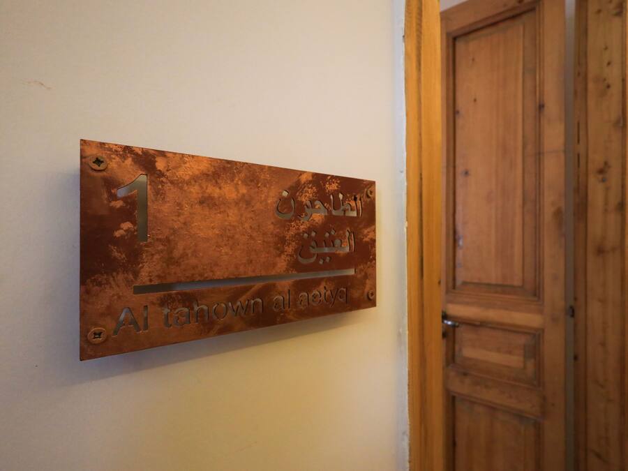 Un letrero de metal con texto en árabe y el número '1' en una pared, junto a una puerta de madera.