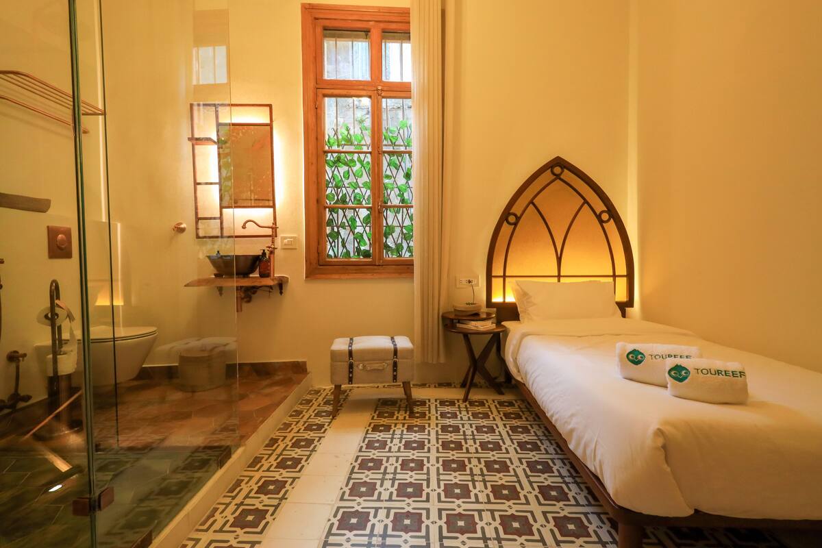 Habitación de hotel con cama, mesita de noche, ventana con vistas, baño con inodoro y zona de ducha.