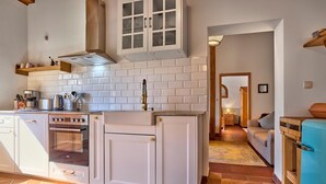 A kitchen with white cabinets, a stove, and a coffee maker. - "Hennenkobel" Apartment with Terrace (Am Kaisersteig Vacation Rentals) (Zwiesel)