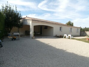 A building with a gravel driveway, outdoor seating area, and a covered patio. - Gîte à Caromb (Caromb)