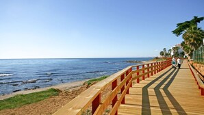 A wooden boardwalk along a beach with a clear view of the ocean.