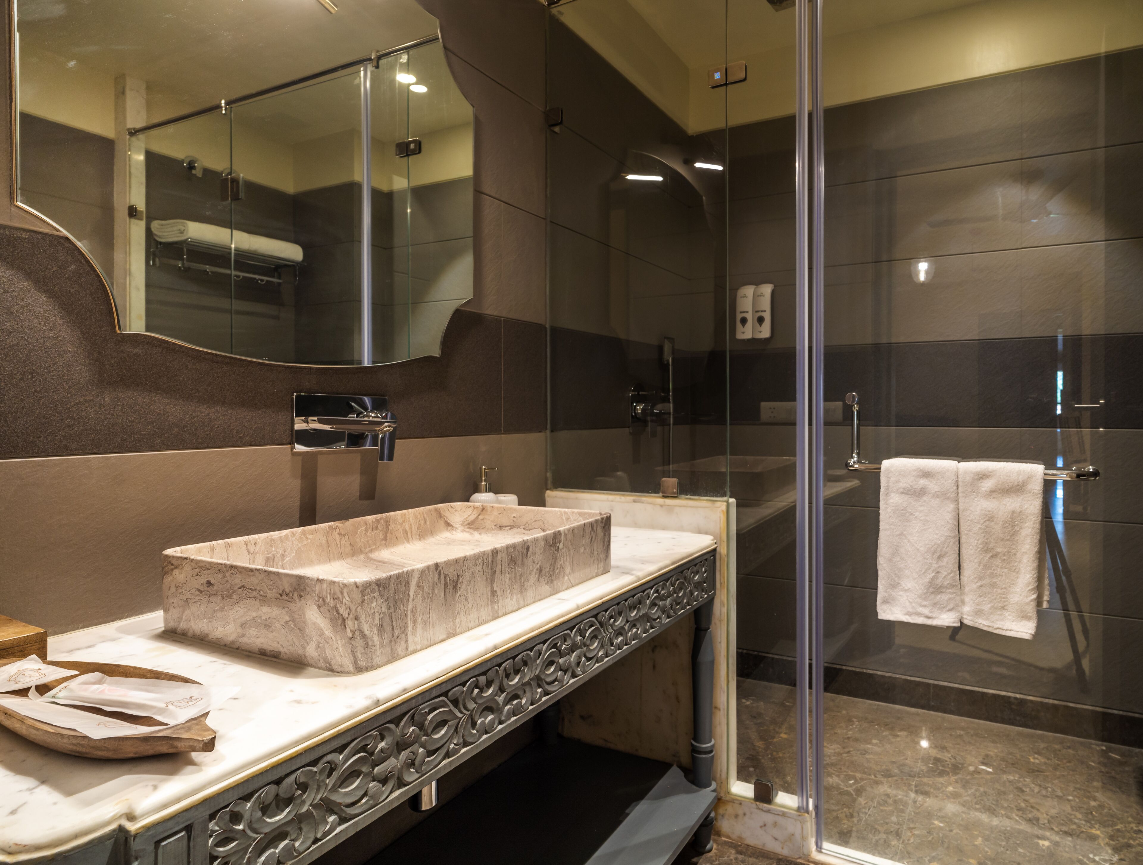 A modern bathroom with a marble sink, a glass shower enclosure, and a large mirror.
