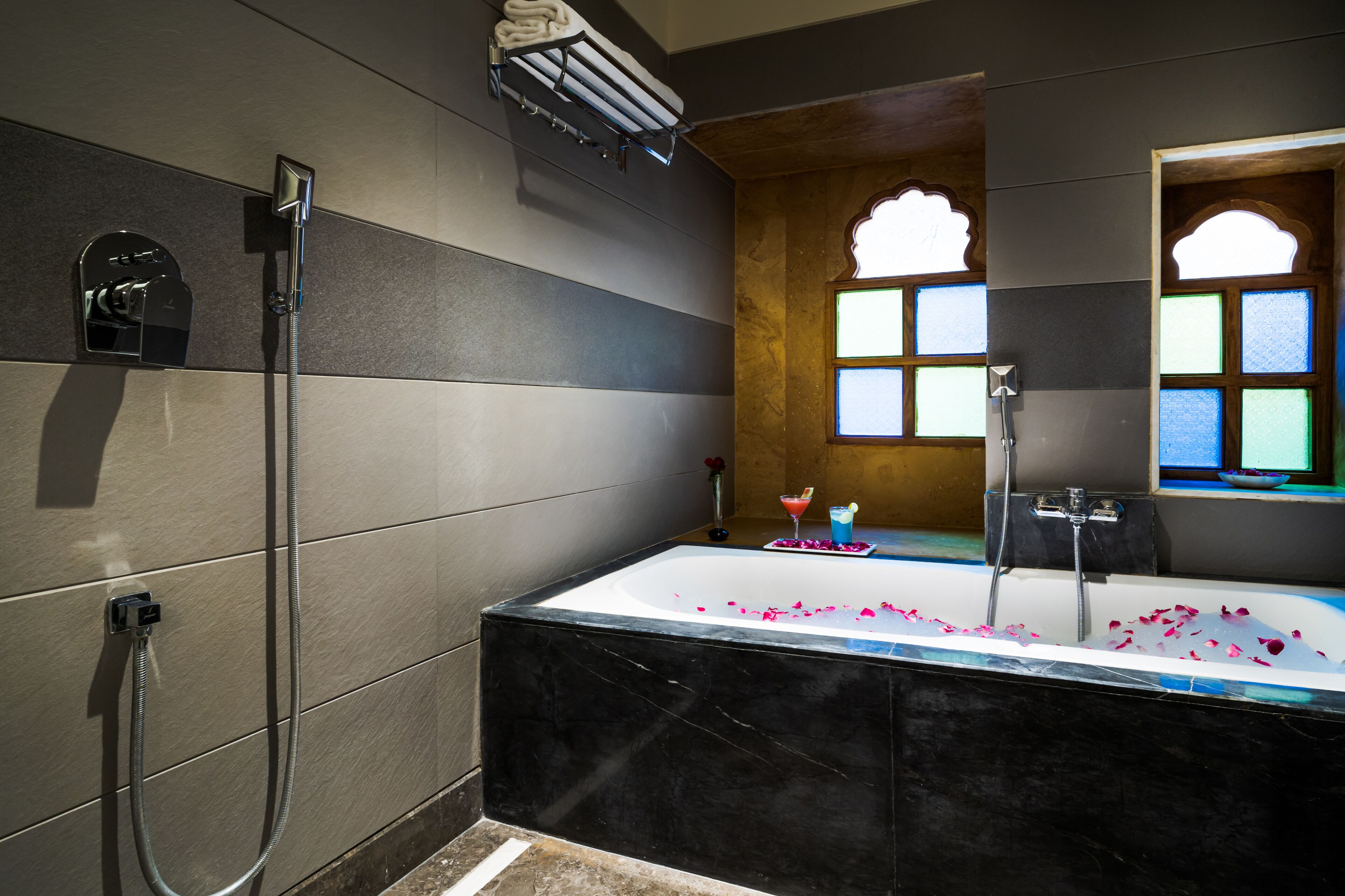Un baño moderno con una bañera grande, ducha y una ventana con vidrieras.