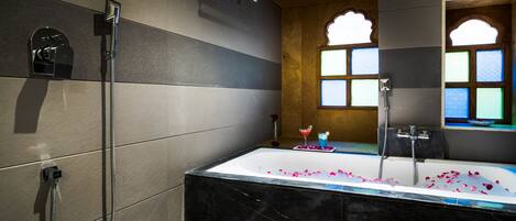 A modern bathroom with a large bathtub, a shower, and a window with stained glass.