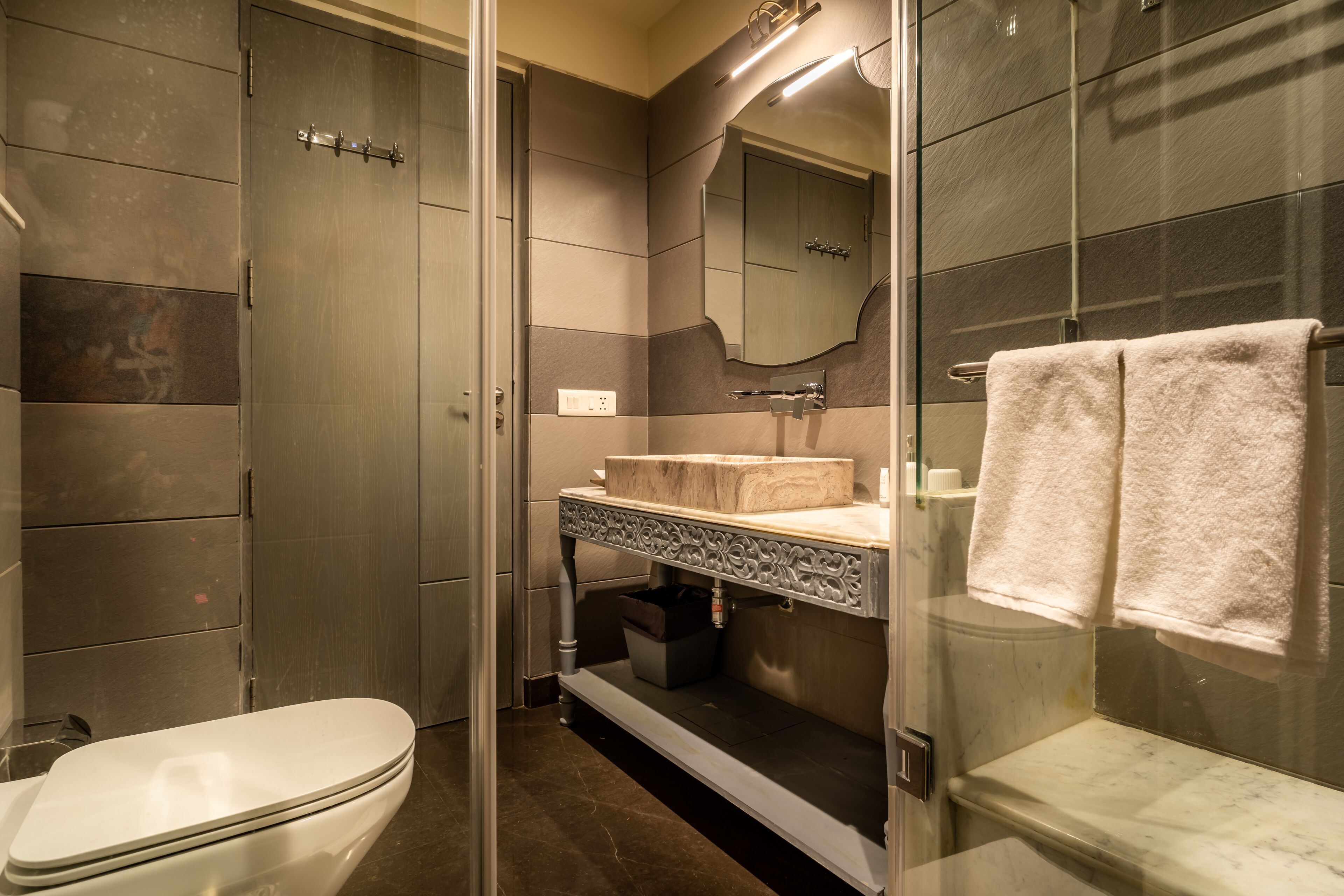 Un baño moderno con cabina de ducha de vidrio, inodoro blanco y tocador con encimera de mármol.