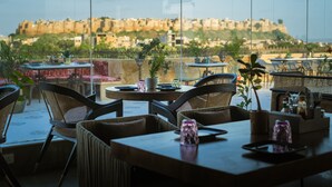 Un restaurante con terraza, mesas, sillas y plantas en macetas.