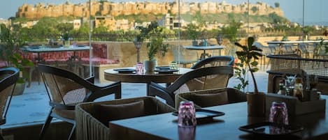 Un restaurante con terraza, mesas, sillas y plantas en macetas.