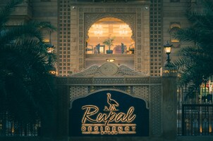 The exterior of the Rupal Residency hotel with a prominent entrance arch and a signboard.