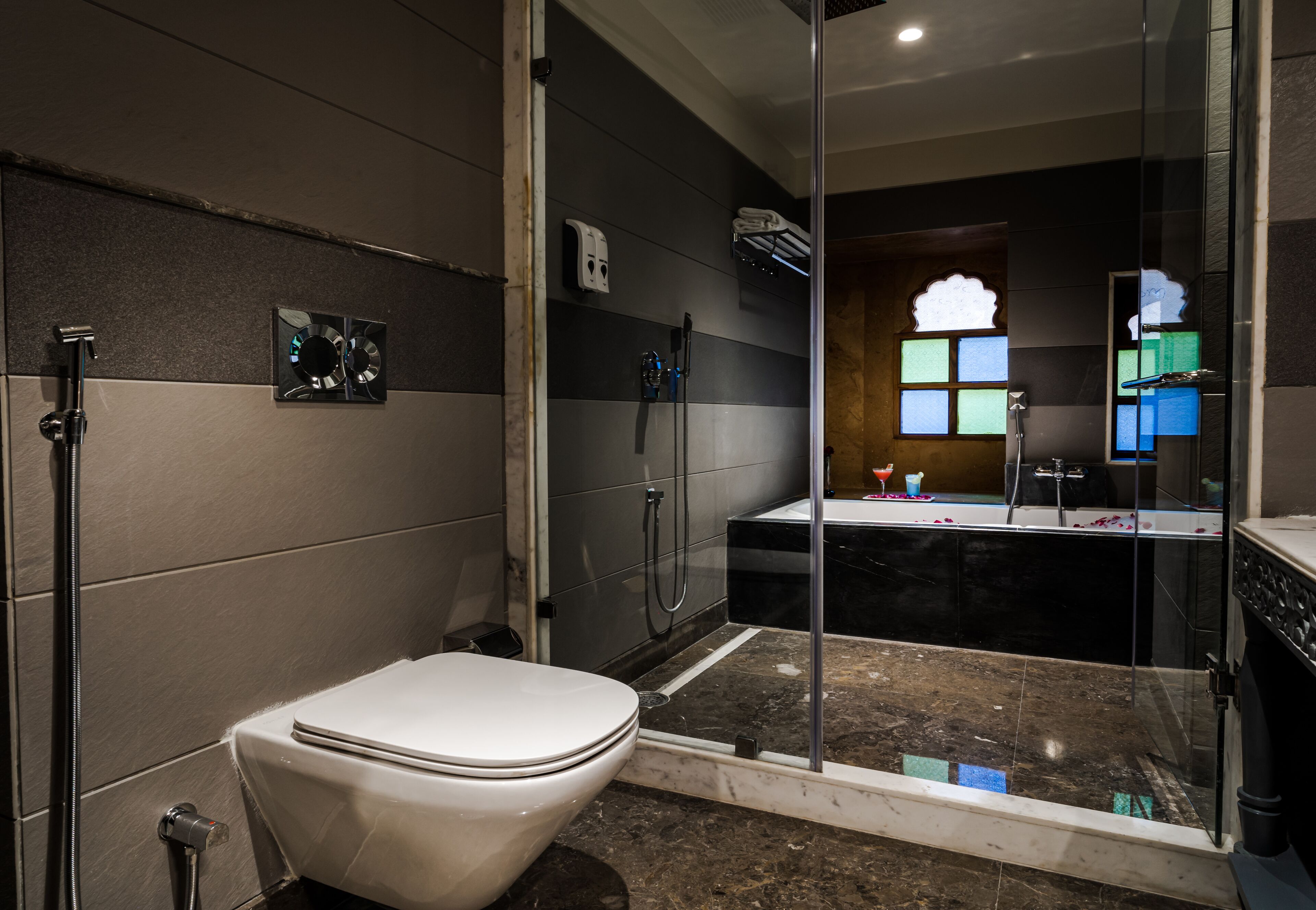 Een moderne badkamer met toilet, douche en een douchecabine met glazen wanden.