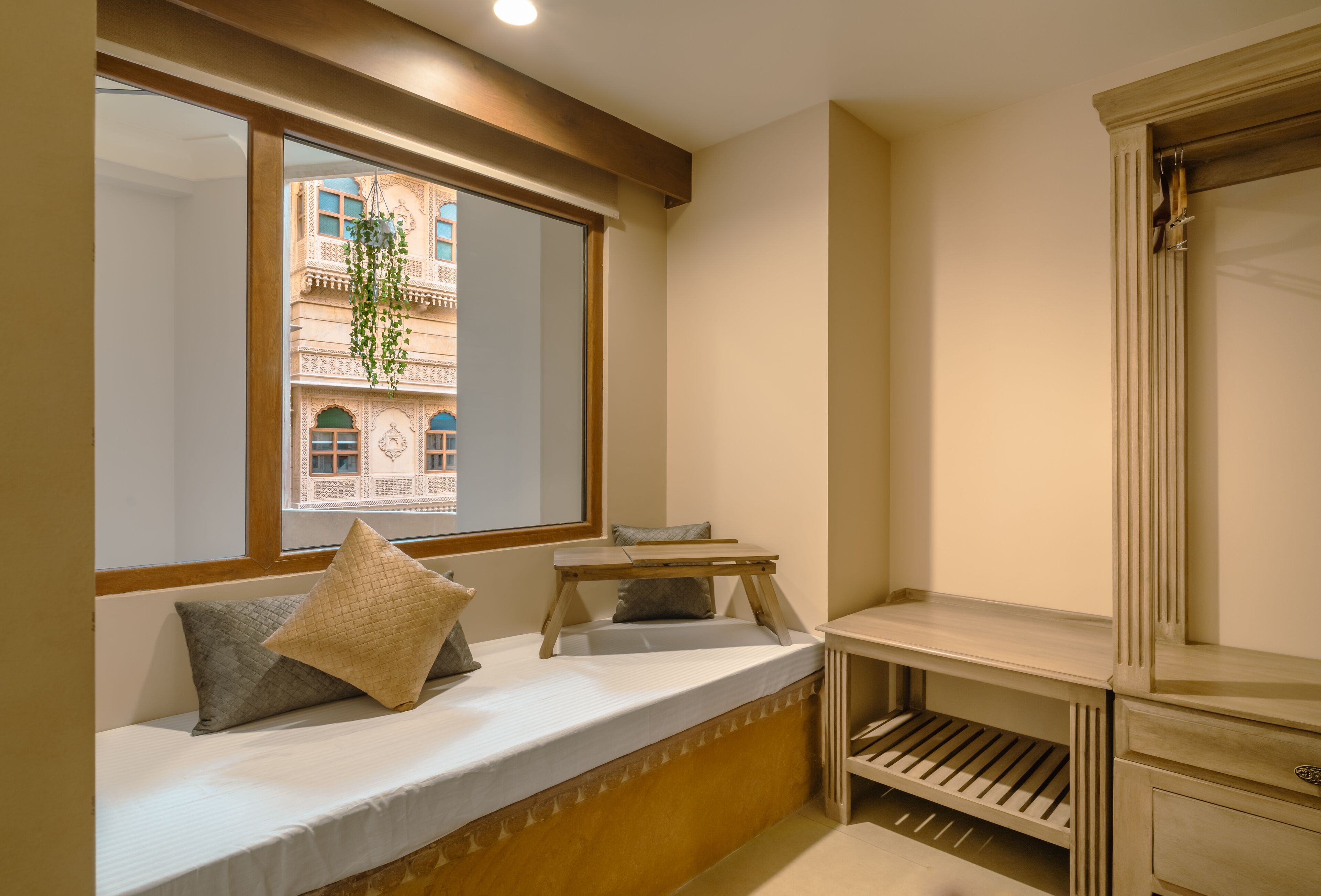 A room with a built-in bench along a window, a small wooden table, and a built-in shelf unit.