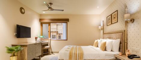 A bedroom with a bed, bedside table, lamp, and a view of a building through a window.