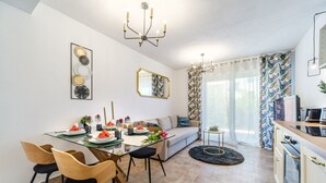 Una cucina moderna con forno integrato, un'area pranzo con tavolo in vetro e sedie in legno, e un soggiorno con divano e tavolino.
