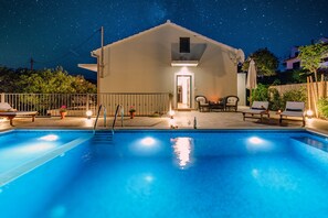 Una piscina con sillas de descanso y un edificio al fondo.