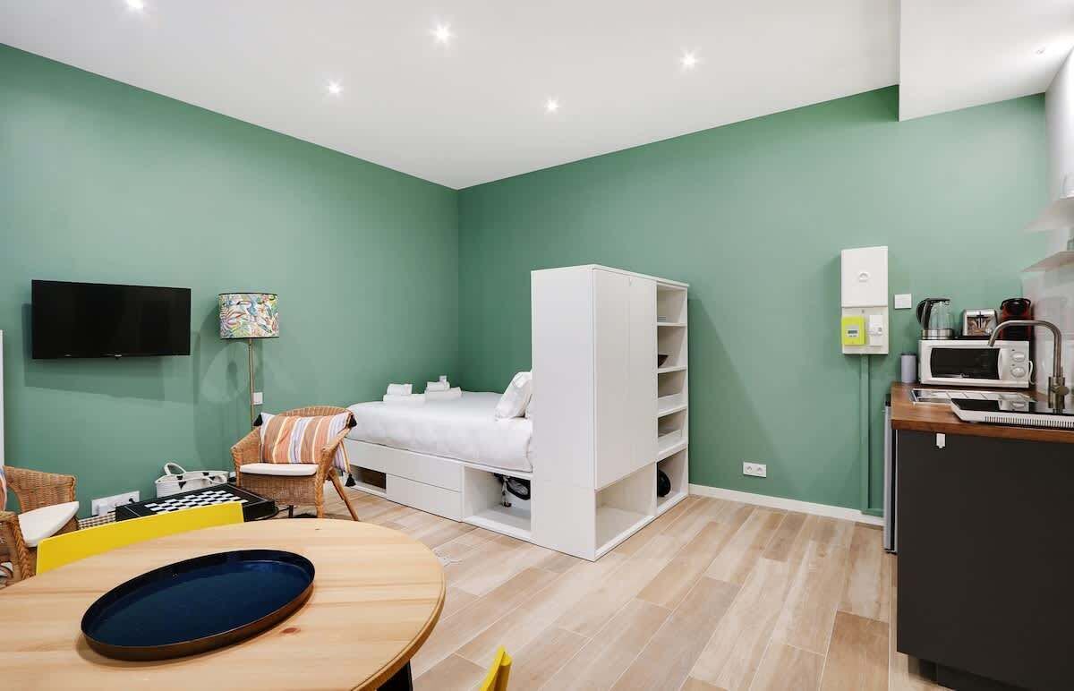 Un espacio habitable compacto con cama, kitchenette y zona de estar.