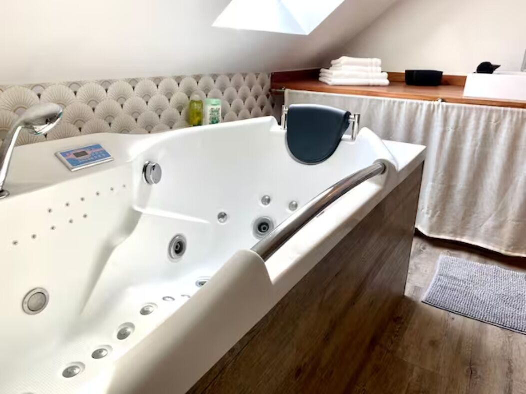 A modern bathroom with a freestanding bathtub, a handheld showerhead, and a control panel.