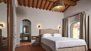 Een slaapkamer met een bed, nachtkastjes, een spiegel en uitzicht door een raam met gordijnen.