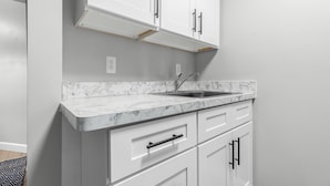 A kitchen with white cabinets, a marble countertop, and a stainless steel sink. - Cozy & Quiet Studio Flat in Historic Mount Clemens (Mount Clemens)