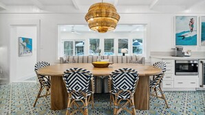 Un comedor con una mesa redonda de madera, sillas con estampado blanco y negro, y un tazón amarillo en el centro.