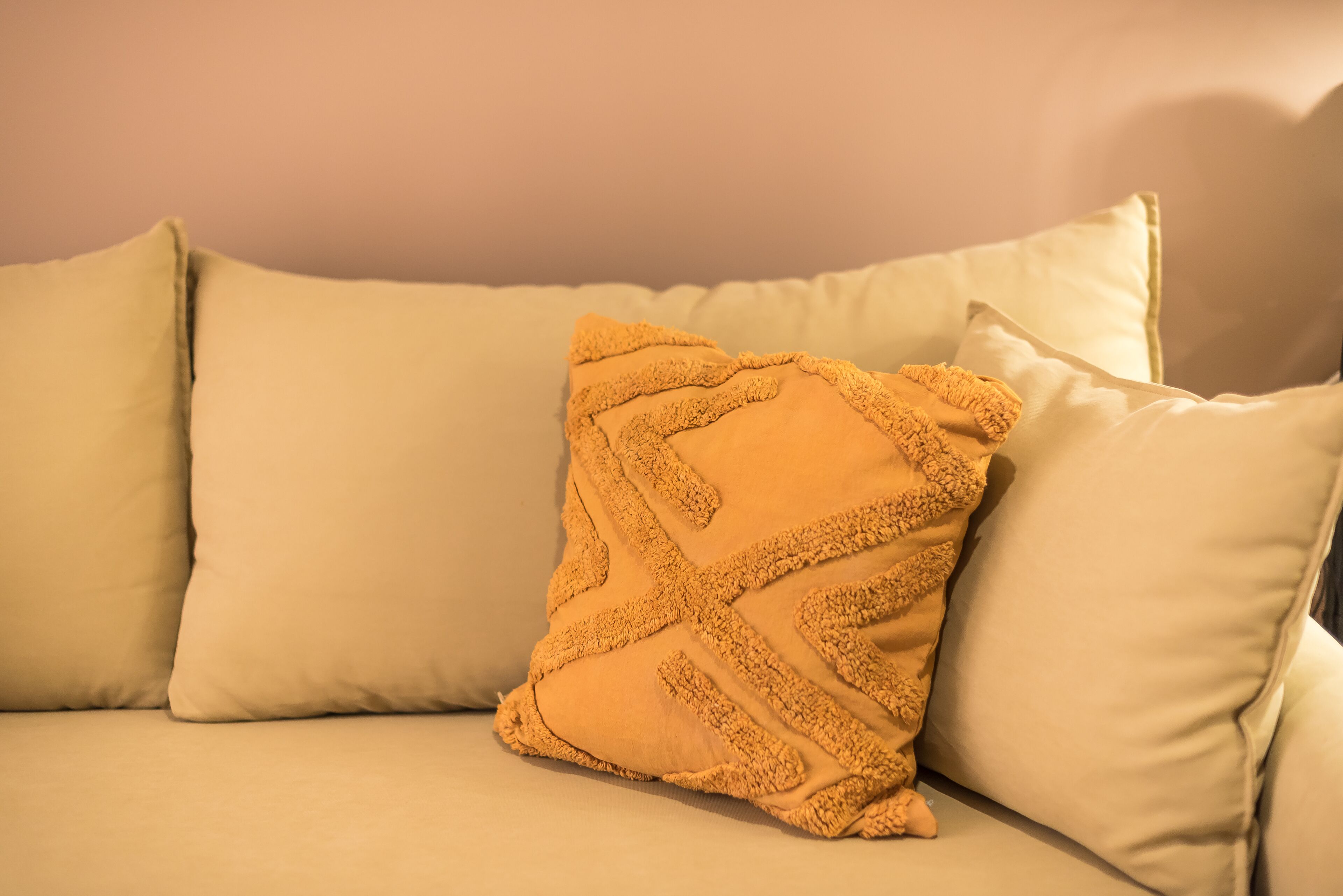 A beige sofa with a single decorative throw pillow.