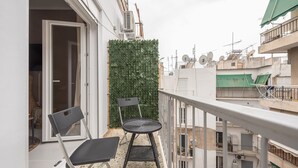 A balcony with two chairs, a small table, and a green wall. - Boho Pennie Home by CloudKeys (Athens)
