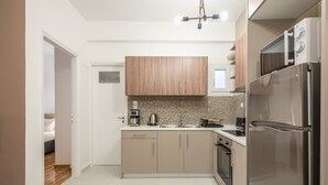 A modern kitchen with wooden cabinets, a stainless steel refrigerator, and a coffee maker. - Boho Pennie Home by CloudKeys (Athens)