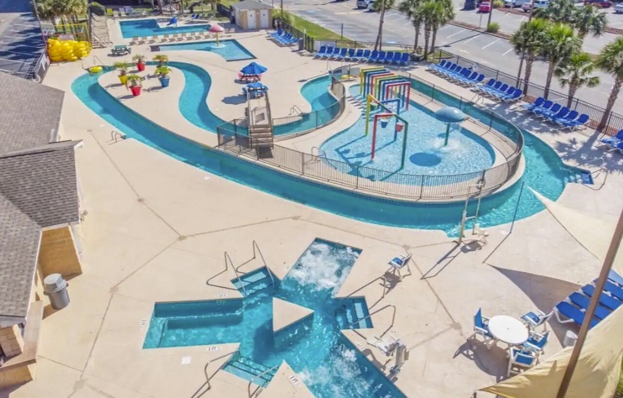 A pool area with multiple swimming pools, lounge chairs, and sun umbrellas.