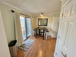 Een kamer met een eettafel, stoelen, een spiegel en een schuifdeur naar een balkon.