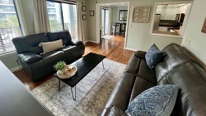 A living room with a ceiling fan, two leather sofas, a coffee table, and a dining area in the background. - Updated Ocean View 2BR|2BA Condo (Myrtle Beach)