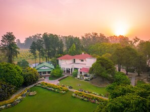 A large, white building with a red roof surrounded by lush greenery and a well-maintained garden.