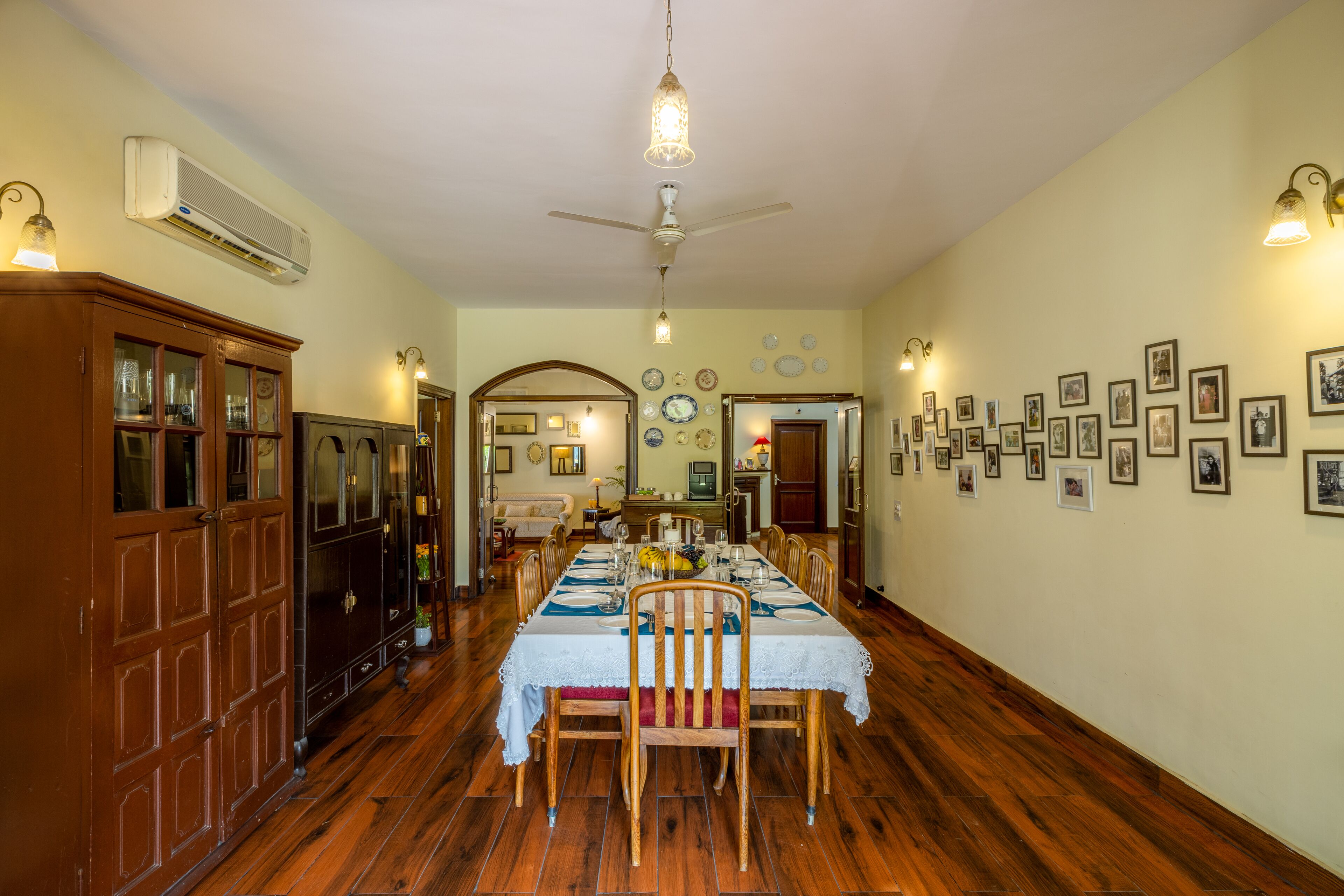 A dining room with a long table set for a meal, wooden cabinets, and wall-mounted lights.